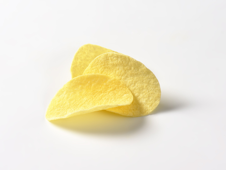 Three thin salted potato chips (crisps) on white backgroundの写真素材
