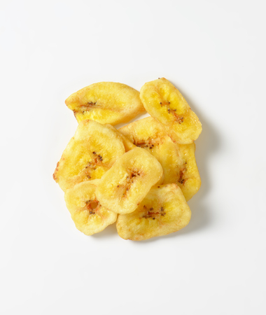 Heap of dried thin banana slices on white backgroundの写真素材