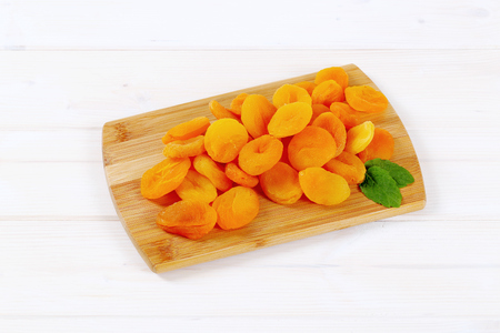 pile of dried apricots on wooden cutting boardの写真素材