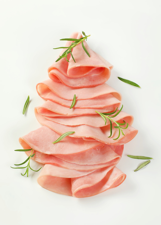 thin slices of ham with fresh rosemary leaves on white backgroundの写真素材