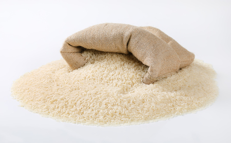 white rice spilling out of burlap bagの写真素材