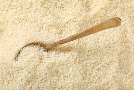 spoon of white long grained rice on rice backgroundの写真素材