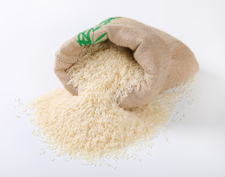 white rice spilling out of burlap bagの写真素材