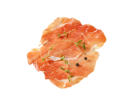 slices of air dried ham with thyme and pepper on white backgroundの写真素材