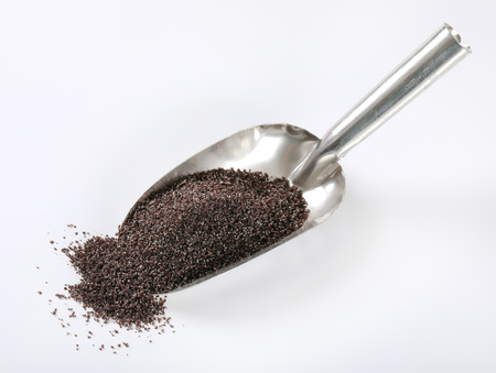 scoop of ground poppy seeds on white backgroundの写真素材
