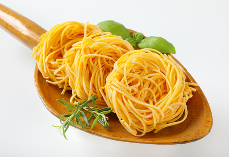 bundles of spaghetti pasta and herbs in wooden scoop - close upの写真素材