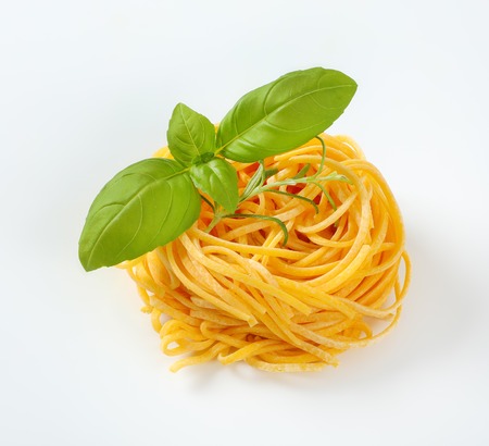 bundle of spaghetti pasta with fresh herbs on white backgroundの写真素材