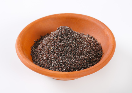 bowl of ground poppy seeds on white backgroundの写真素材
