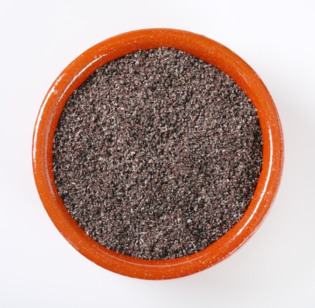 bowl of ground poppy seeds on white backgroundの写真素材