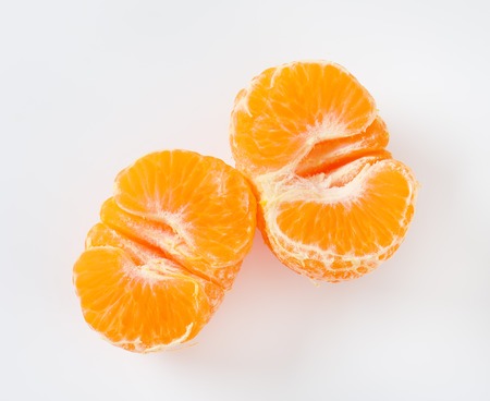 halved peeled tangerine on white backgroundの写真素材