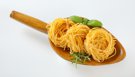 bundles of spaghetti pasta and herbs in wooden scoopの写真素材