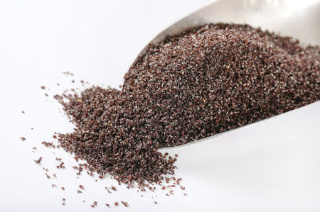 scoop of ground poppy seeds on white background - close upの写真素材