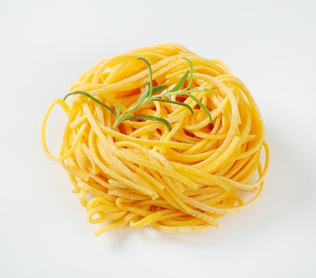 bundle of spaghetti pasta with rosemary on white backgroundの写真素材