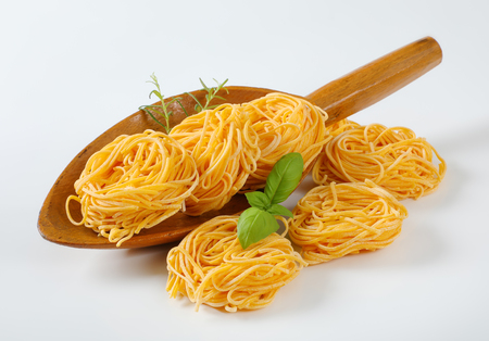 bundles of spaghetti pasta and herbs in wooden scoopの写真素材