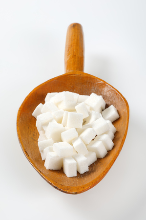 scoop of white sugar cubes on white backgroundの写真素材