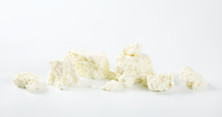 pieces of crumbly white cheese on white backgroundの写真素材