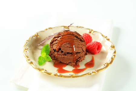 Scoop of chocolate ice cream with toffee sauce and raspberriesの写真素材