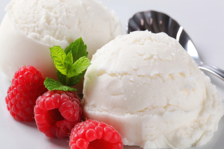 Two scoops of white ice cream with fresh raspberriesの写真素材