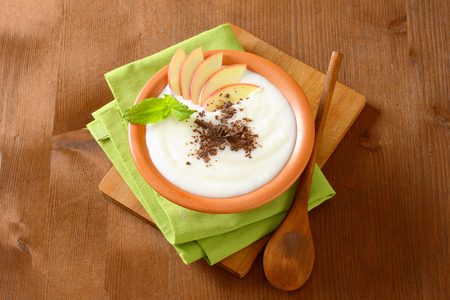 Bowl of milk pudding with apple slices and grated chocolateの写真素材