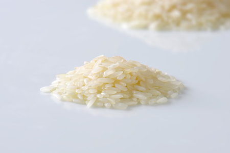 Heap of raw rice on white backgroundの写真素材
