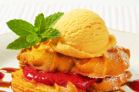 Spritz butter cookies with raspberry sauce and scoop of yellow ice creamの写真素材