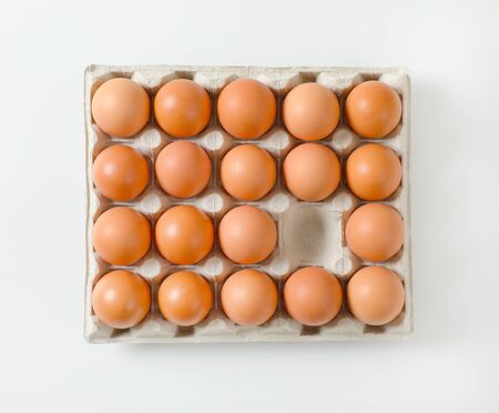 Carton of fresh brown eggs, one egg missingの写真素材
