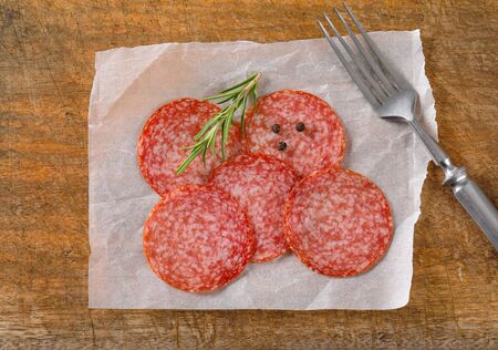 Sliced salami sausage on white wax paperの写真素材