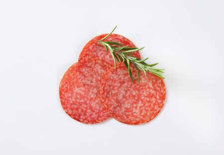 Thin slices of Hungarian salami and fresh rosemaryの写真素材