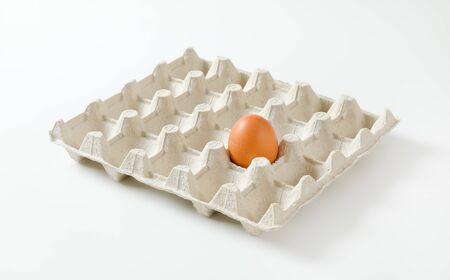 One brown egg left in a twenty dimpled egg trayの写真素材