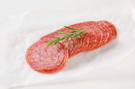 Sliced salami sausage on white wax paperの写真素材