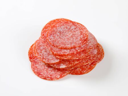 Thinly sliced salami sausage on white backgroundの写真素材