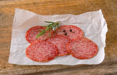 Sliced salami sausage on white wax paperの写真素材