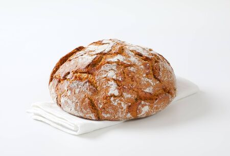 Loaf of rustic sourdough bread on white napkin
