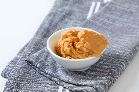 Bowl of crunchy peanut butter on gray napkin