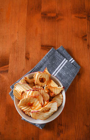 Bowl of dried apple slices - apple chips or rings - on gray napkin