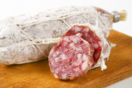 Dry cured French sausage on wooden cutting boardの写真素材