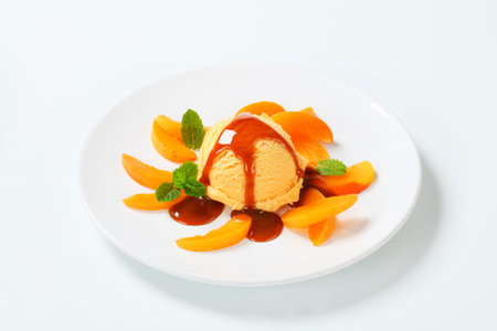 Ice cream with fresh apricot slices and caramel sauceの写真素材