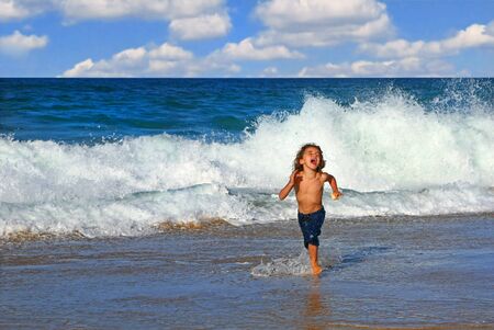 Young Happy Boy Running in the Ocean Surfの写真素材