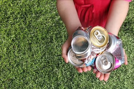 Aluminum Cans Crushed For Recycling in a Childs Handsの写真素材