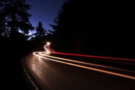 Car Light Trails in the Mountains on a Starry Night Alongside the Highway. Noise is Present in the...