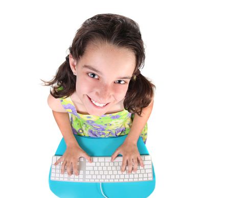 Cute Little Girl Typing on a Computer Keyboard Looking Up on White Backgroundの写真素材