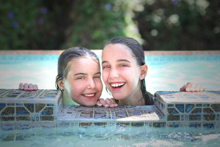 Smiling Young Kids in a Swimming Pool During Summer. Image is Slightly Soft.の写真素材