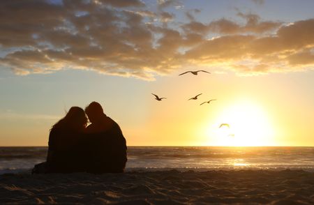 Loving Happy Couple Watching the Sunset in Love on the Beachの写真素材
