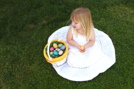 Little Girl With Eggs in Her Easter Basket Outdoors in the Grassの写真素材