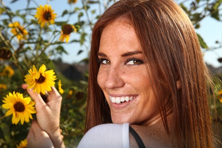 Beautiful Red Haired Woman Outdoors in a Sunflower Fieldの写真素材