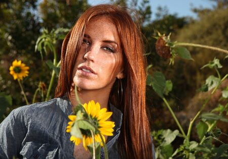 Beautiful Red Haired Woman Outdoors in a Sunflower Fieldの写真素材