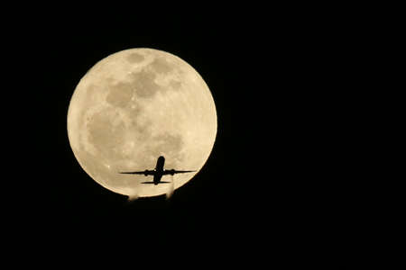 Commercial Jet Airplane Passing in front of a Full Moon- Real not Digitally Alteredの写真素材