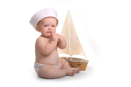 Crying and Sad Baby Sitting up Wearing Sailor Hat on White Backgroundの写真素材