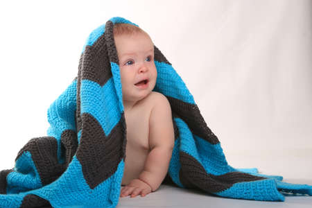 Adorable Baby Smiling Lying on Stomach With Blanket on White Backgroundの写真素材