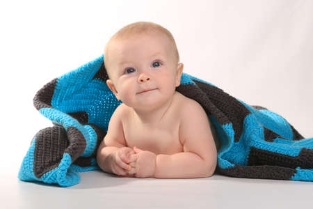 Adorable Baby Smiling Lying on Stomach With Blanket on White Backgroundの写真素材
